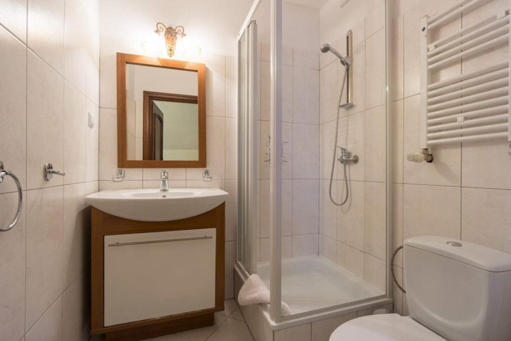 Compact tiled bathroom with glass shower enclosure, sink vanity under mirror, and toilet.