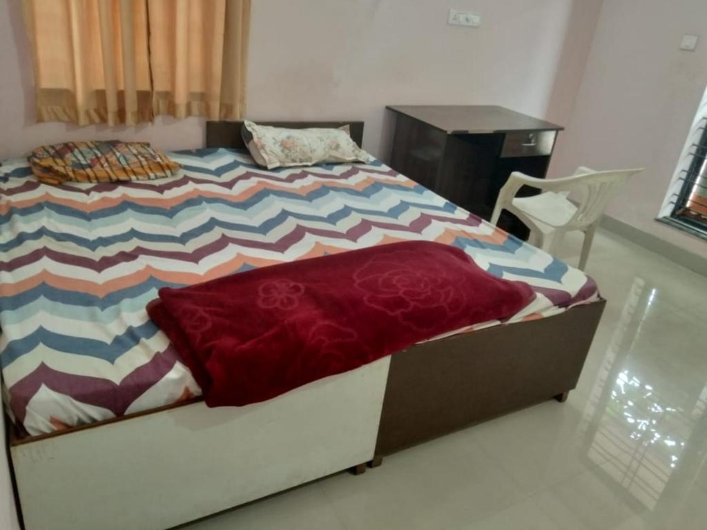 a bedroom with a bed with a desk and a chair at Agarwal Guest House in Naya Raipur