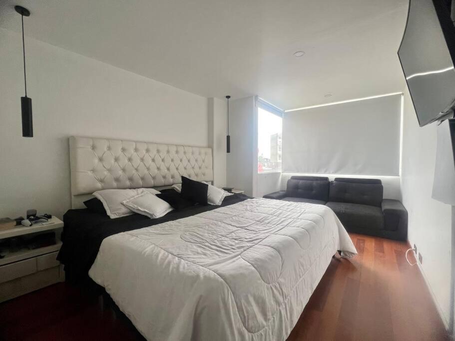 um quarto com uma cama grande e um sofá em Galeras 103 em Bogotá