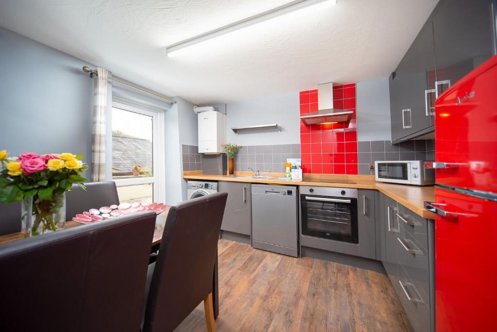 uma cozinha com um frigorífico vermelho e uma mesa com cadeiras em Royd Cottage at Lower Aylescott em West Down