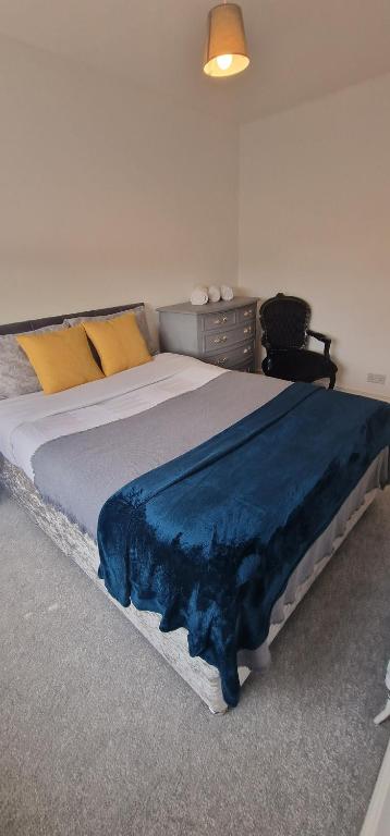 a bedroom with a large bed with a blue blanket on it at Cosy Fresh New Refurbished House in Doncaster