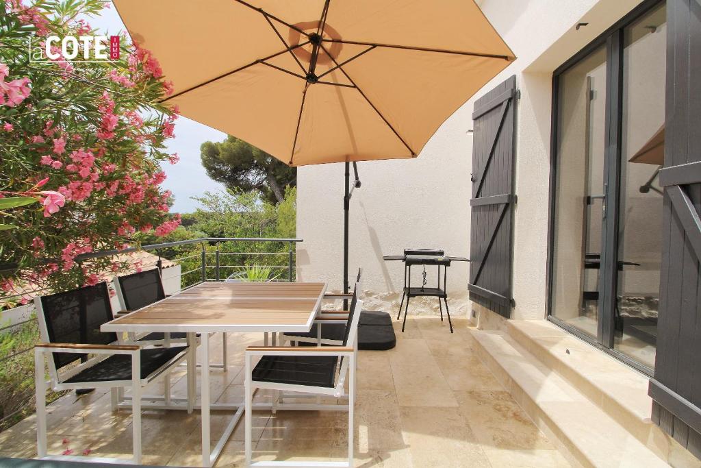 un patio avec une table, des chaises et un parasol dans l'établissement LA PASTISSIERE BIS - 4 COUCHAGES, à Carry-le-Rouet