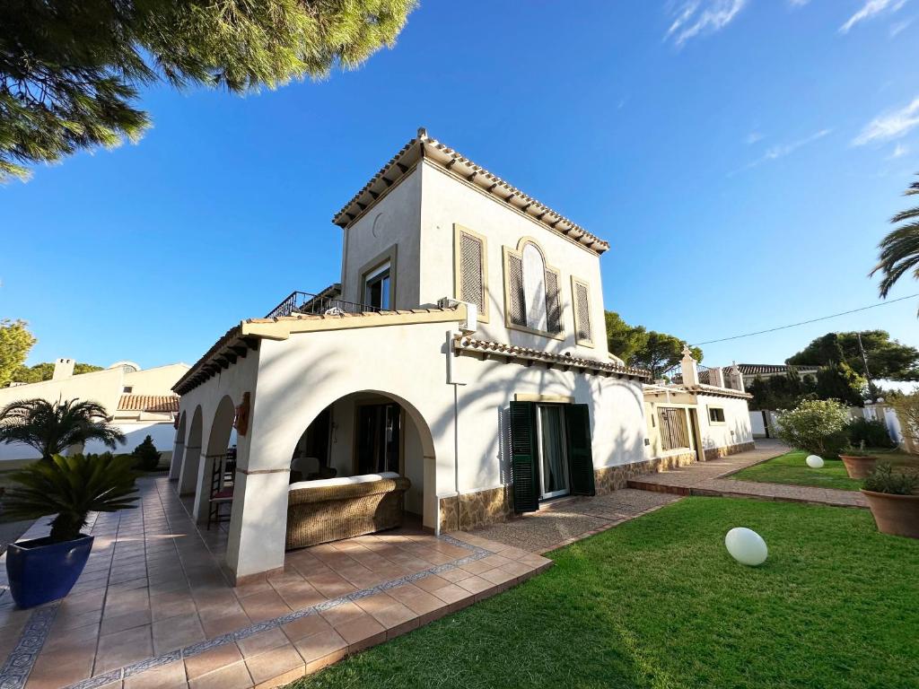 una casa blanca con un arco en un patio en Chalet Villa Mediterránea a 75 metros de la playa., en Orihuela