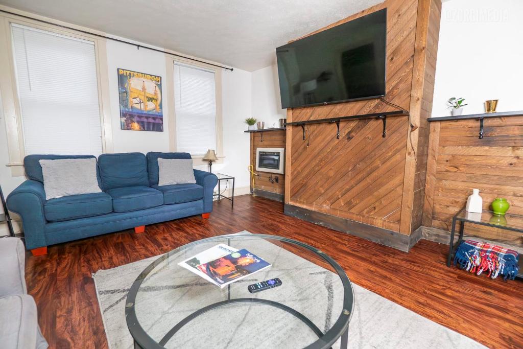een woonkamer met een blauwe bank en een tv bij 1 BR - Parking - Amazing View Nearby! in Pittsburgh