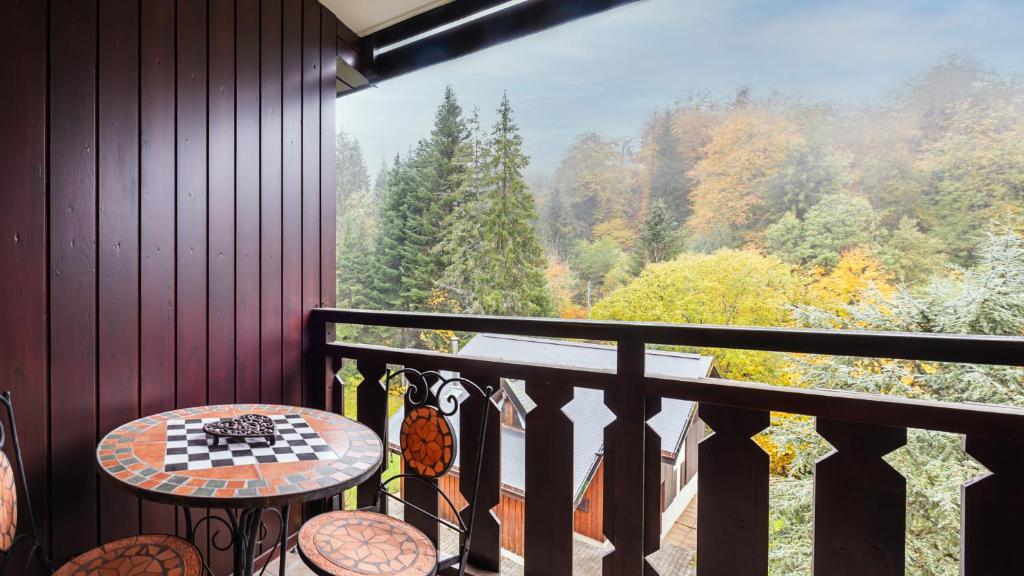 a balcony with a table and a view of the forest at Grande Neige 39 - pied des pistes 4 pers in Morillon