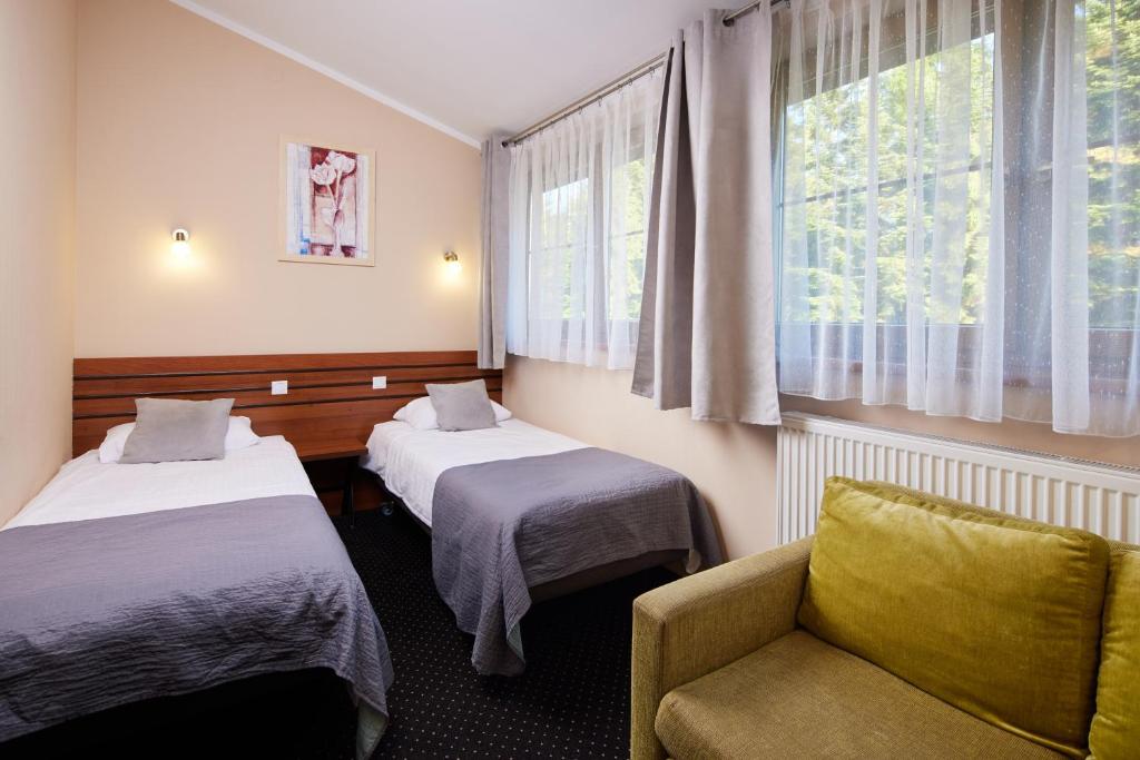 Pokój z 2 łóżkami, krzesłem i oknem w obiekcie Hotel Beskidzki Raj Medical SPA w mieście Stryszawa