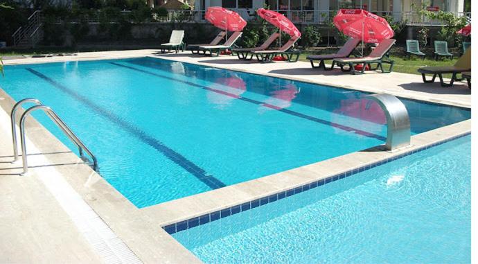 a large swimming pool with lounge chairs and umbrellas at begonvil evleri in Antalya