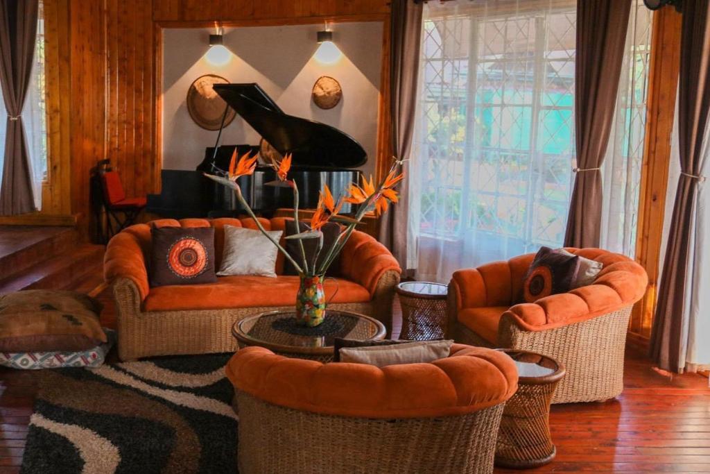 uma sala de estar com sofás laranja e uma mesa em Zamani za kale em Kabuku