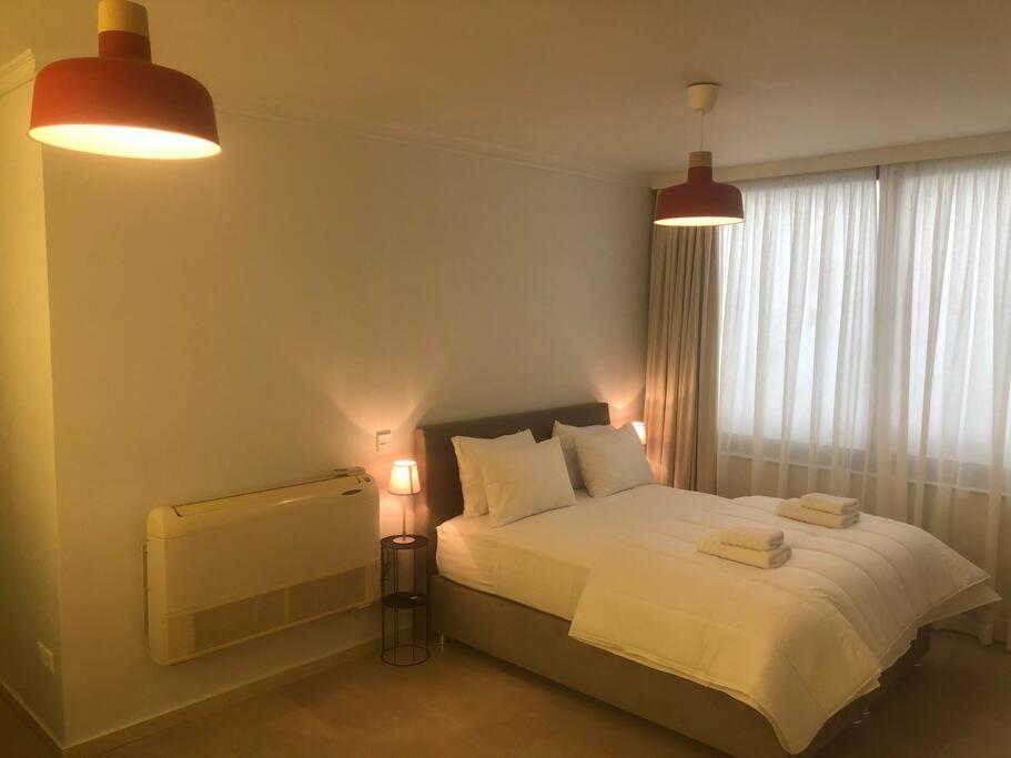 ein Schlafzimmer mit einem Bett mit zwei Lampen und einem Fenster in der Unterkunft Tsakalof 10 Central Apartment by SuperHost Hub in Athen