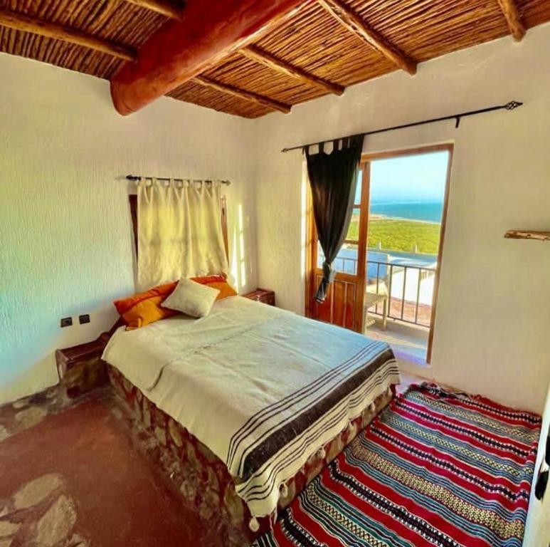 a bedroom with a bed with a view of the ocean at SurfcampLagrotte in Essaouira
