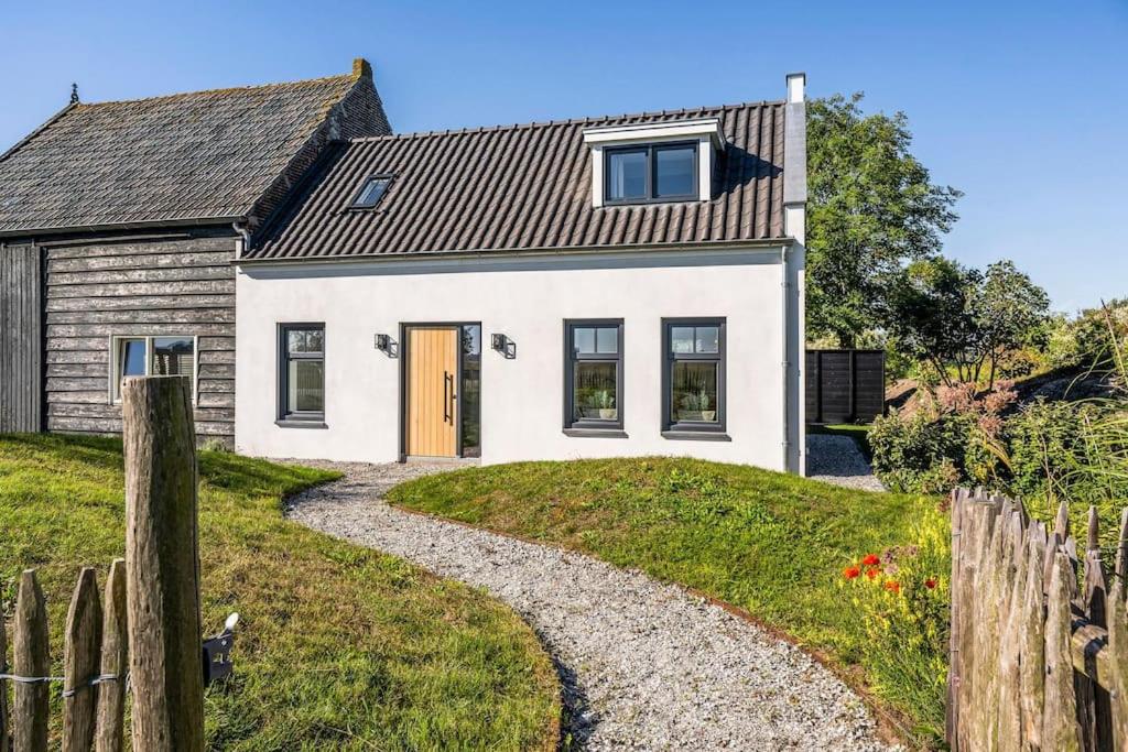 Casa blanca con valla y entrada de grava en Huisje Bries, Nieuw! mooi uitzicht, vlakbij strand, en Ouddorp