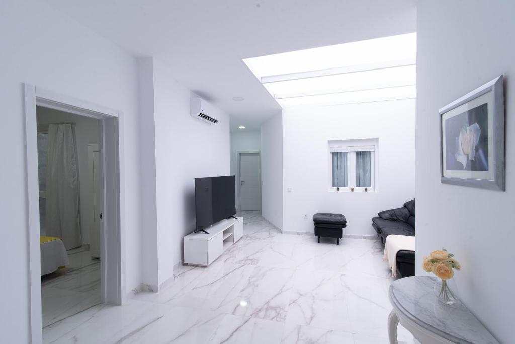 ein weißes Wohnzimmer mit einem TV und einem Sofa in der Unterkunft Isle Home By CanariasGetaway in Guanarteme