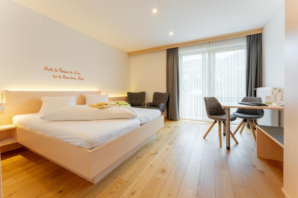 una camera d'albergo con letto, tavolo e sedie di Stampferhof a Weissensee