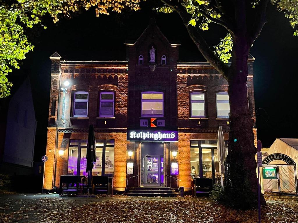 un edificio de ladrillo con una tienda delante de él por la noche en Becky´s Kolpinghaus, en Recklinghausen