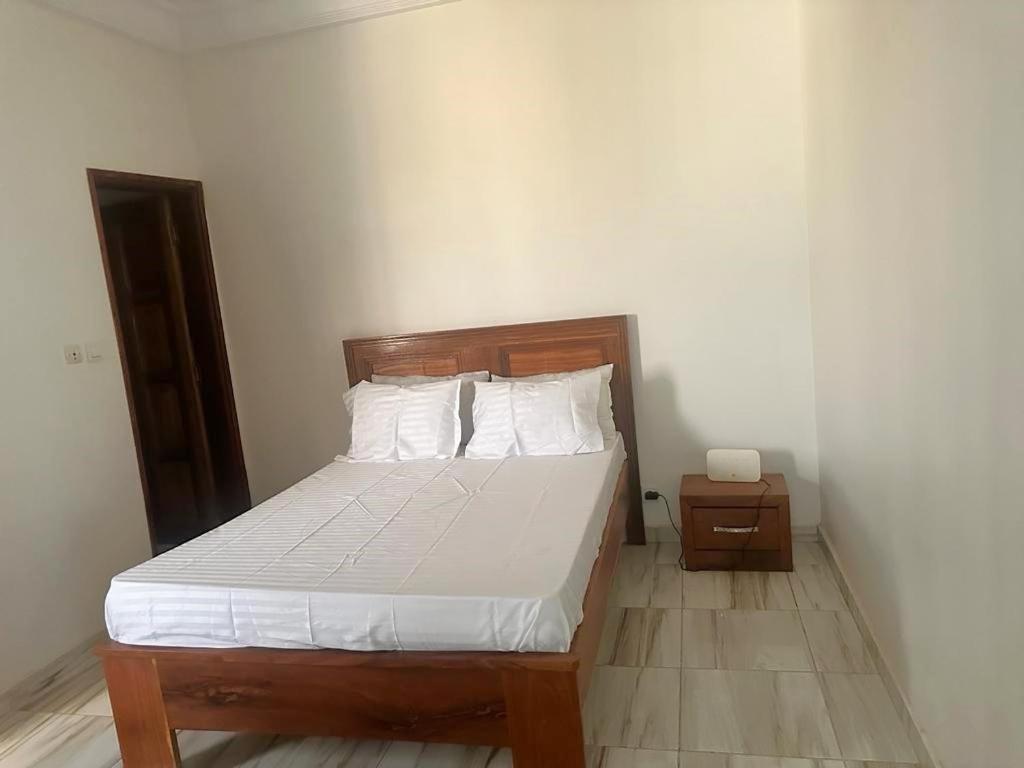 Una cama con sábanas blancas y almohadas en un dormitorio en Studio Moderne Dakar Keur Ndiaye LÔ, en Dakar