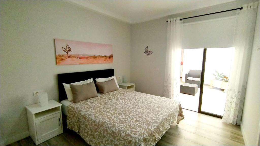 ein weißes Schlafzimmer mit einem Bett und einem Fenster in der Unterkunft Apartamento El Puerto del Médano in El Médano