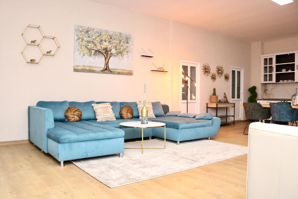 ein Wohnzimmer mit einem blauen Sofa und einem Tisch in der Unterkunft Herman Apartment Cisnadie in Cisnădie