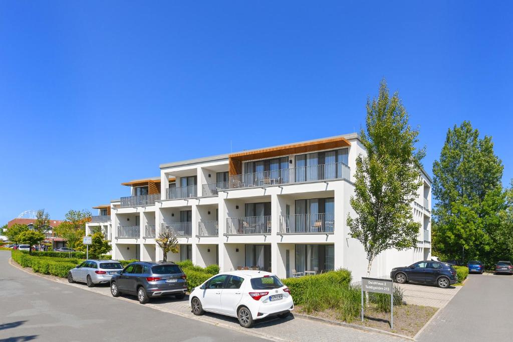 a white building with cars parked in front of it at Ferienwohnung Ankergold im Deichhaus in Bensersiel