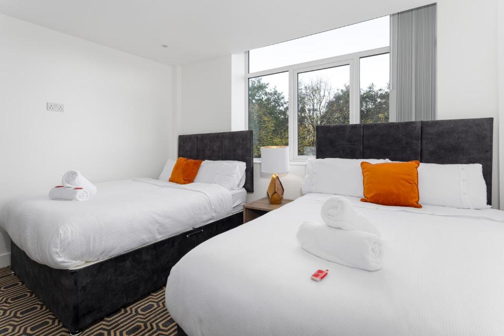 Flatzy - 16 Guests 4 En-suite Central Apartment B في ليفربول: غرفة نوم بسريرين مع وسائد برتقالية وبيضاء