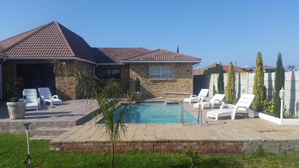 een huis met een zwembad met stoelen eromheen bij Ebenezer Guesthouse Bluewater Bay in Port Elizabeth