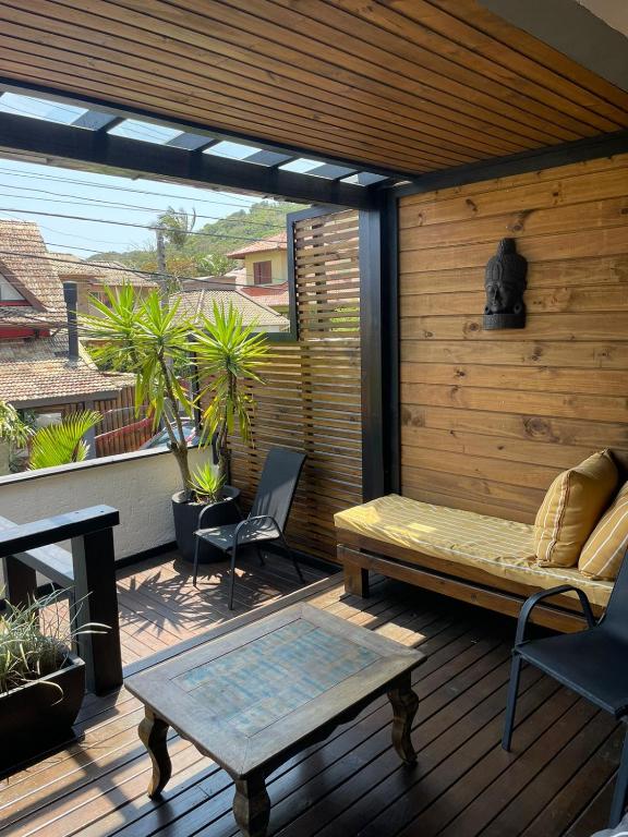 a patio with a bench and a table on a deck at BeMyGuest Floripa in Florianópolis
