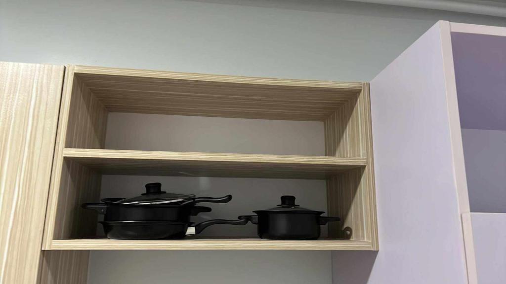 two pots and pans sitting on a shelf at Iza's Alabang Studio Apartment in Manila