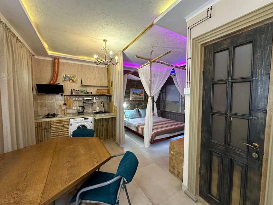 a kitchen with a wooden table and a bedroom at City Center Beach side Hut in Tbilisi City
