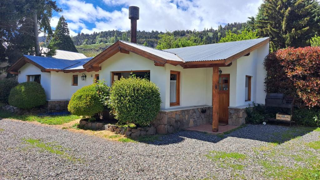 uma pequena casa branca com um telhado de metal em La Colella em San Martín de los Andes