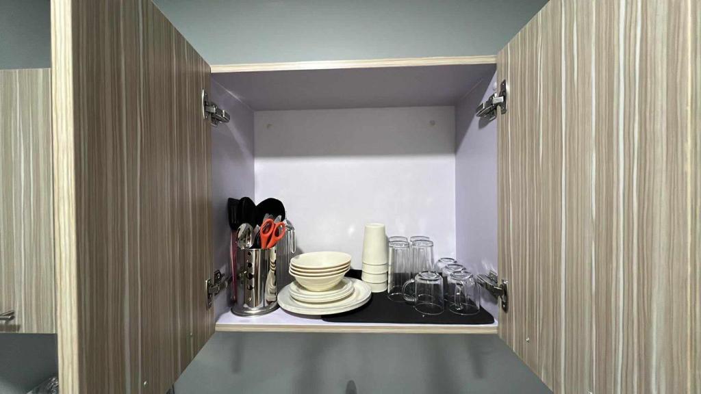 a cupboard with plates and utensils in it at Iza's Condo in Filinvest Alabang in Manila