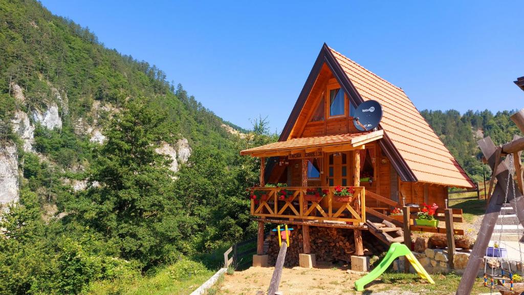 uma pequena casa de madeira com um parque infantil numa montanha em Tarska čarolija Zaovine em Popovići