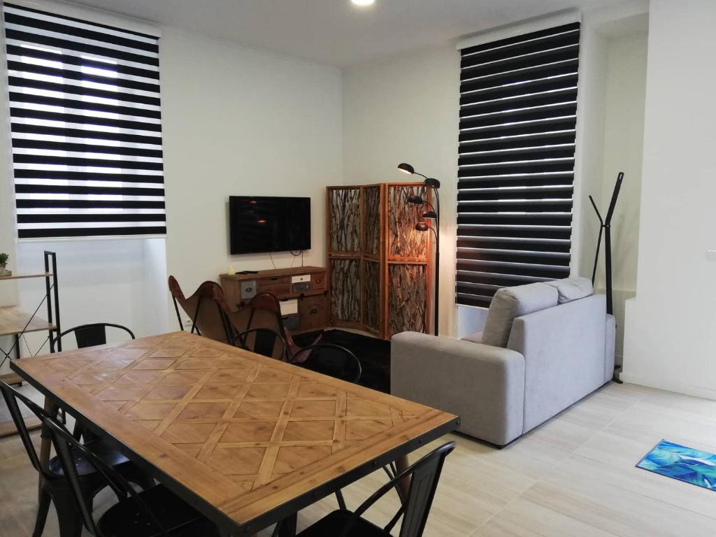 uma sala de estar com uma mesa, um sofá e uma televisão em Azores Calheta Inn T2 Frente Boa Nova em Ponta Delgada