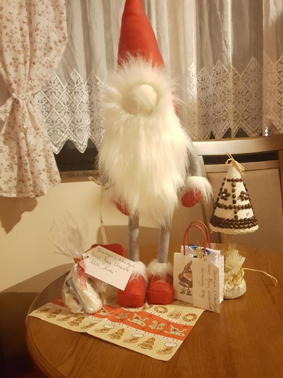 Festive table display with tall plush gnome, small gift bags and handcrafted cone-shaped ornament.