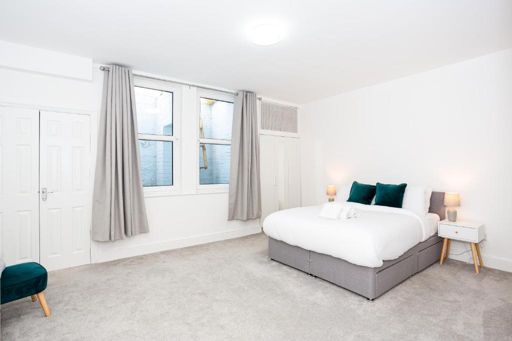 サウスエンド・オン・シーにあるZen Apartmentsの白いベッドルーム(ベッド1台、窓2つ付)