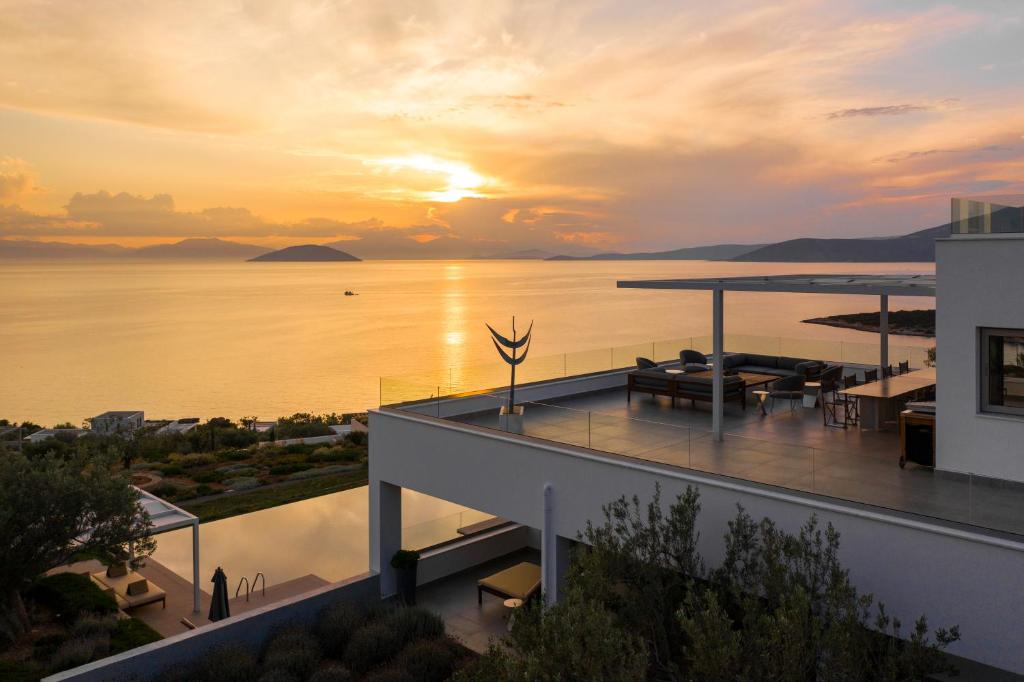 uma vista para um edifício com um pôr-do-sol sobre a água em Villa Artemis - New Magnificent Beachfront Villa with Infinity Pool! em Kranidi