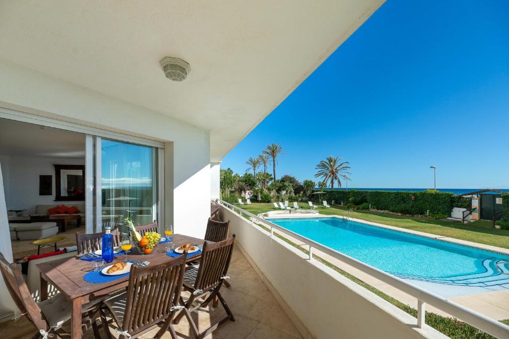 um pátio com uma mesa e cadeiras ao lado de uma piscina em HomeForGuest beach apartment in Puerto Banus Marbella em Marbella