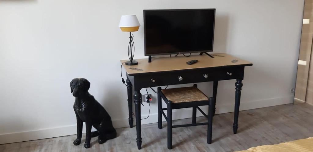 un escritorio con un perro negro sentado junto a una lámpara en Chambre dorée, en Pleurtuit