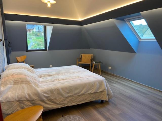 a bedroom with a large bed and two windows at Les Herbes Flottantes in Englesqueville-en-Auge