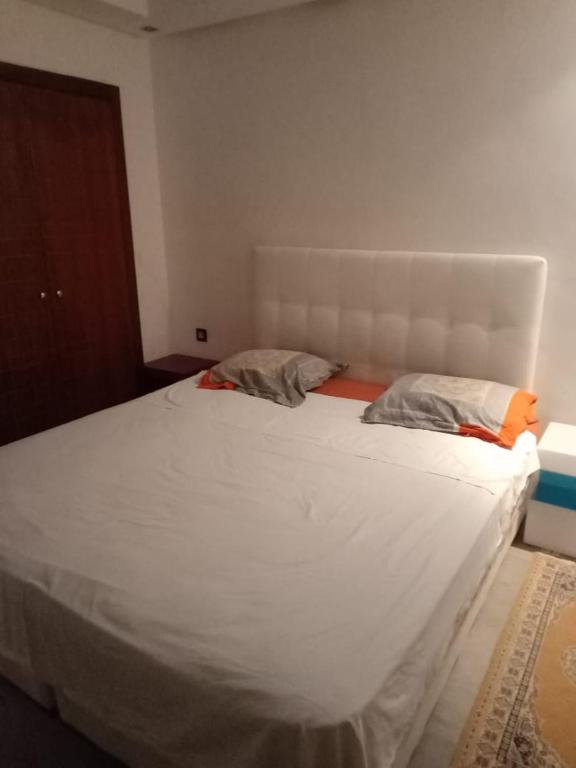 een slaapkamer met een groot wit bed met 2 kussens bij appartement haut standing à gueliz in Marrakesh