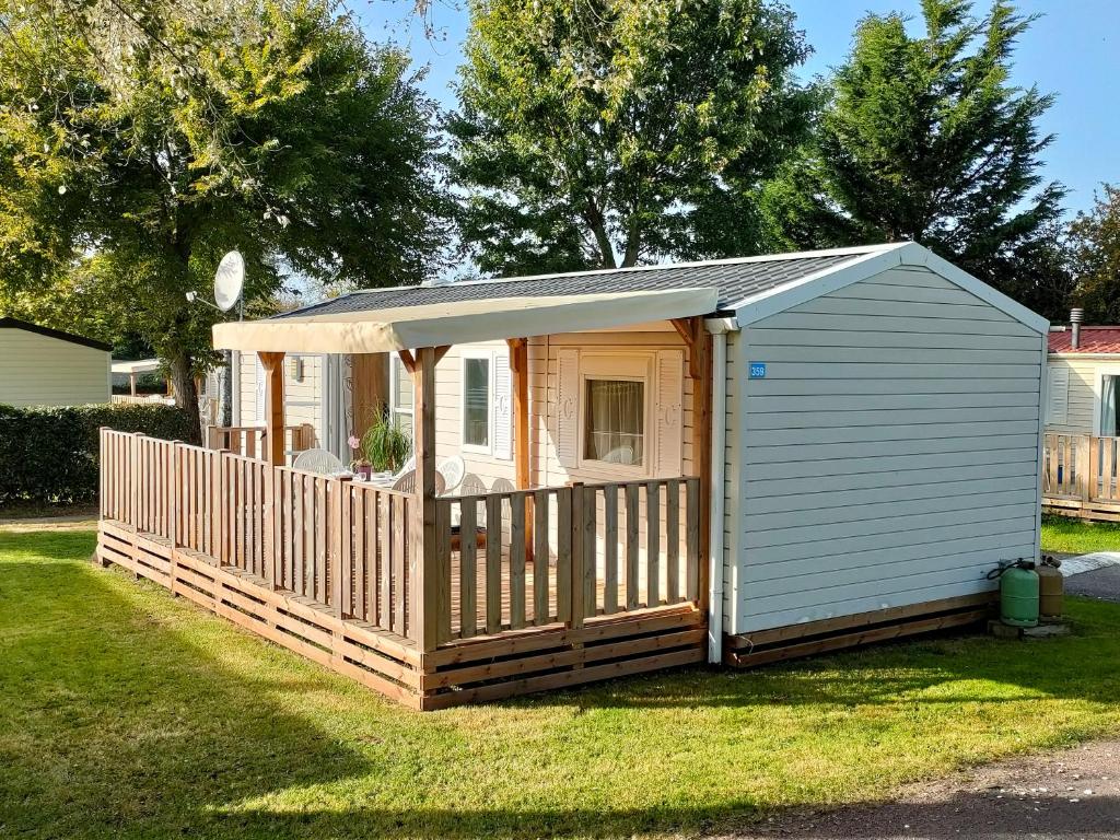a small shed with a porch on the grass at LJ Cosy Lodge - Mobilhome in Houlgate