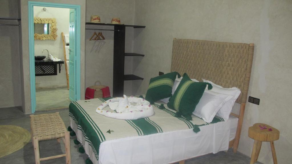 a bedroom with a bed with green and white pillows at Family Village Marrakech in Marrakech