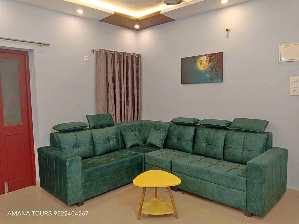 a living room with a green couch and a yellow stool at 2bkh Ahmedabad in Ahmedabad
