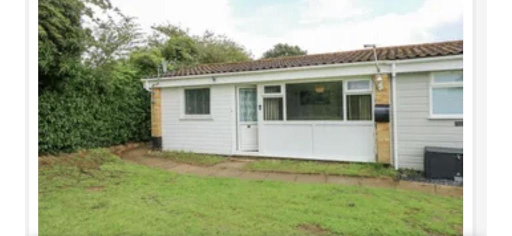 a small white house with a yard at Kingfisher Holiday Park 1 Waveney Valley Great Yarmouth in Gorleston-on-Sea