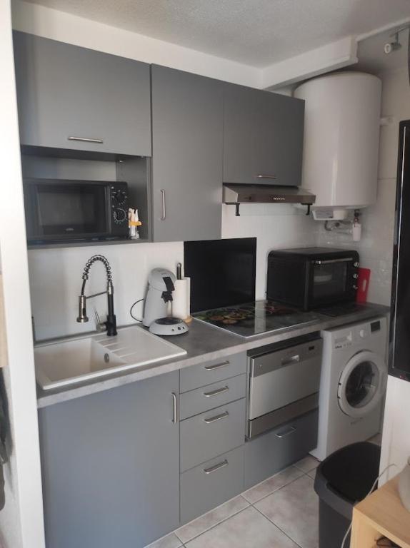 a kitchen with a sink and a stove and a microwave at Charmant appartement à Sainte Marie la mer (66470) in Sainte-Marie-Plage
