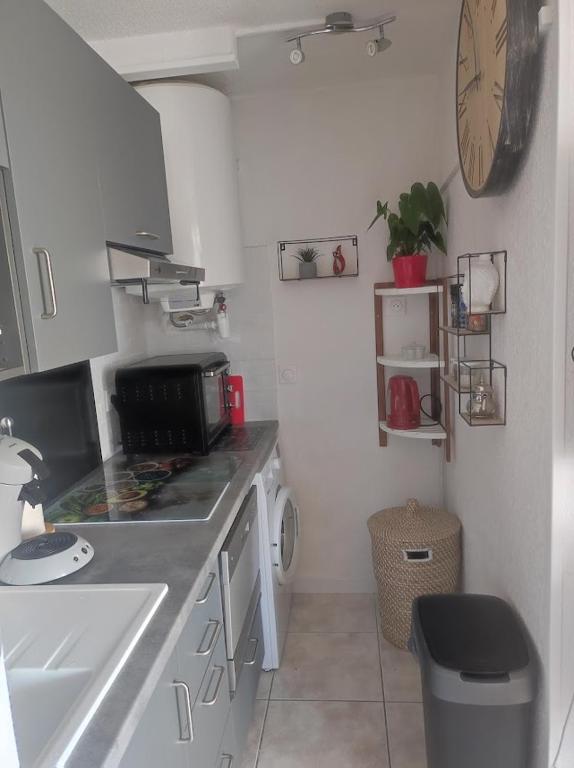 a kitchen with a sink and a clock on the wall at Charmant appartement à Sainte Marie la mer (66470) in Sainte-Marie-Plage