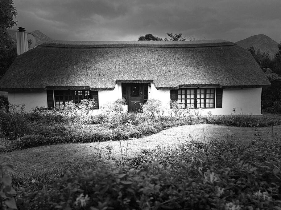 une photo en noir et blanc d'une maison avec un toit en gazon dans l'établissement The Cottage on West, à Greyton