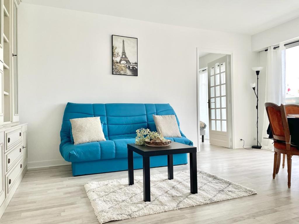 Sofá azul en la sala de estar con mesa en Appartement 2 pièces proche Enghien-Les-Bains, en Soisy-sous-Montmorency