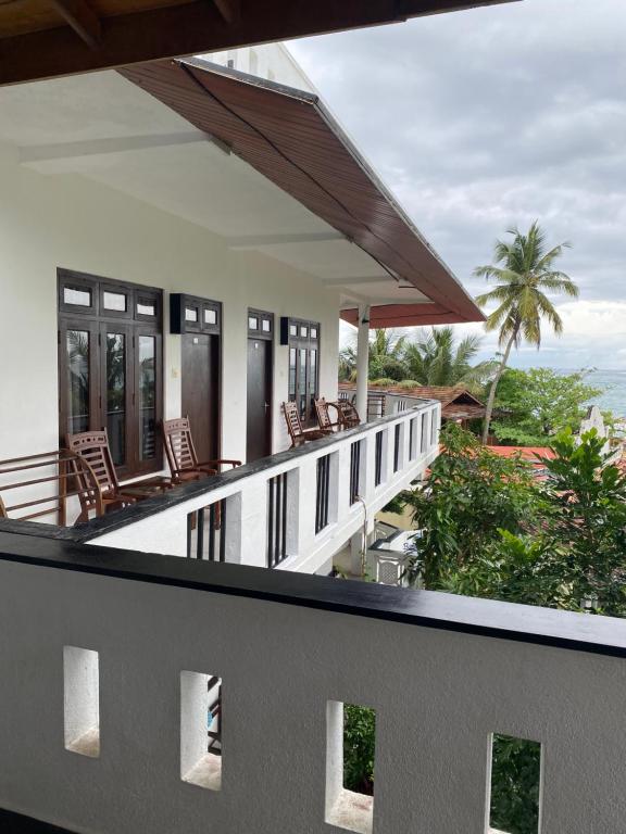 a balcony of a house with chairs and the ocean at Unawatuna Beach Bungalow - in Unawatuna