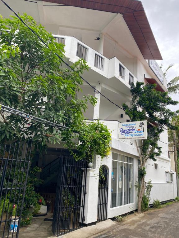 a white building with a gate in front of it at Unawatuna Beach Bungalow - in Unawatuna