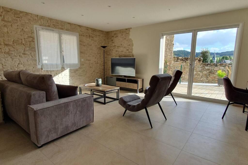 un salon avec un canapé, des chaises et une télévision dans l'établissement La Petite Germaine, à Fontaine-sur-Ay