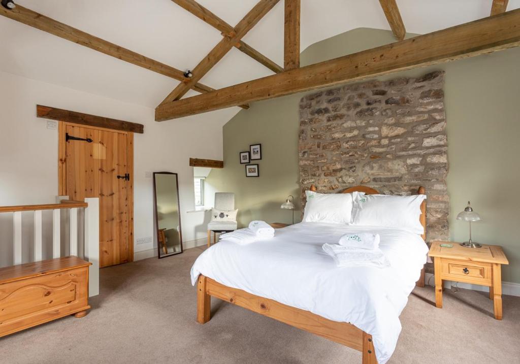 a bedroom with a large bed and a stone wall at Ivy Cottage in Low Eskcleth